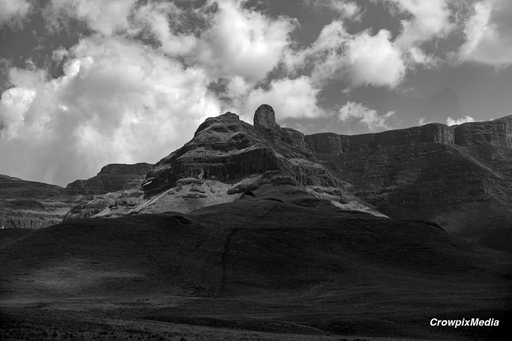 alt="Form is shown the the natural shapes of the rock in the mountains pictured above. Black and white photograph of mountains"