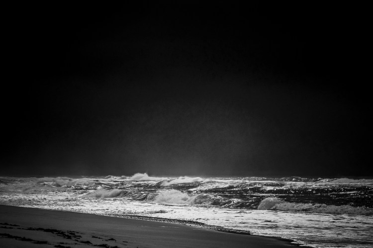 alt="black-and-white ocean and beach photograph"