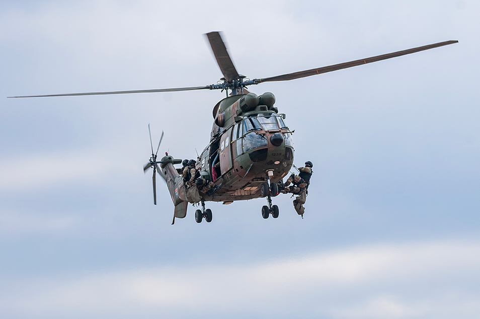 alt="South African soldiers disembark from Rooivalk helicopter during a battle simulation demonstration at the Africa Aerospace and Defence expo 2024."