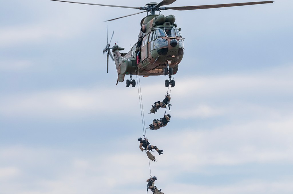 alt="South African soldiers disembark from Rooivalk helicopter during a battle simulation demonstration at the Africa Aerospace and Defence expo 2024."